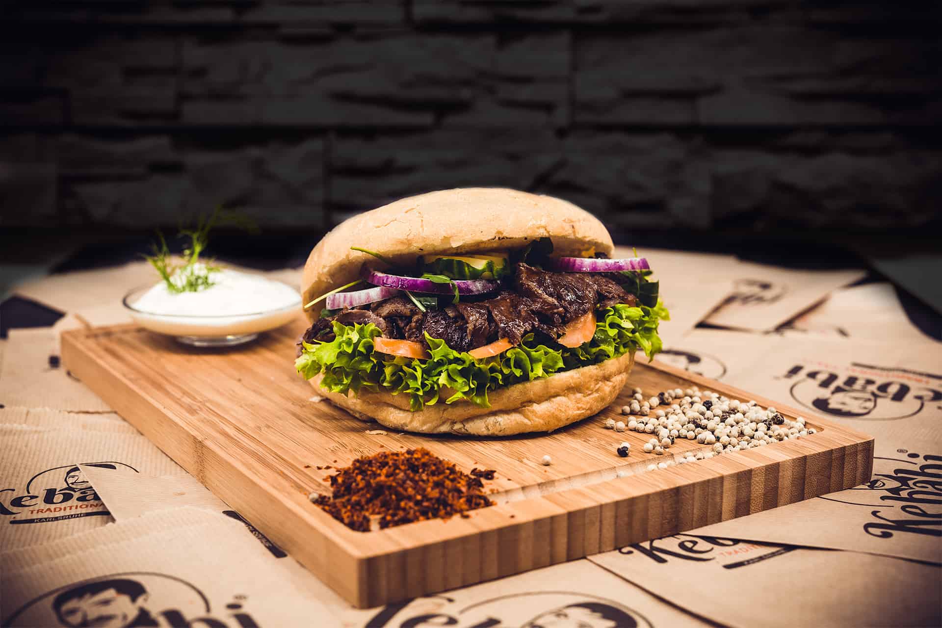 kebabi Fladenbrot mit kebabi kebab und salat auf einem holzbrett vor dunklem Hintergrund